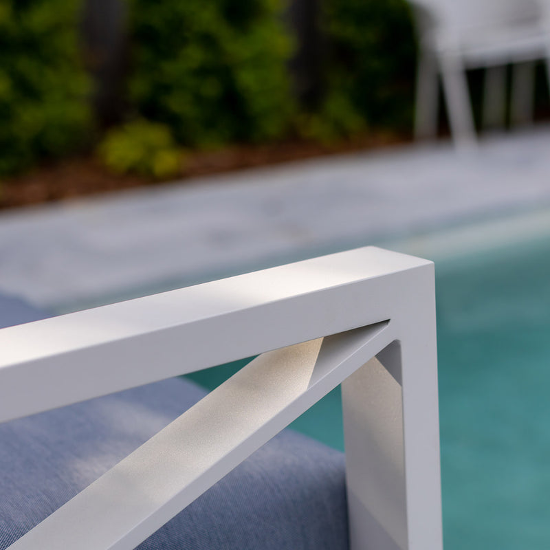 Close up of aluminium outdoor furniture from Linear Lounge collection, featuring white frame and light grey cushions by the pool.